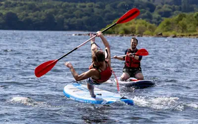 Person falling off a paddle board on Derwentwater in the Lake District