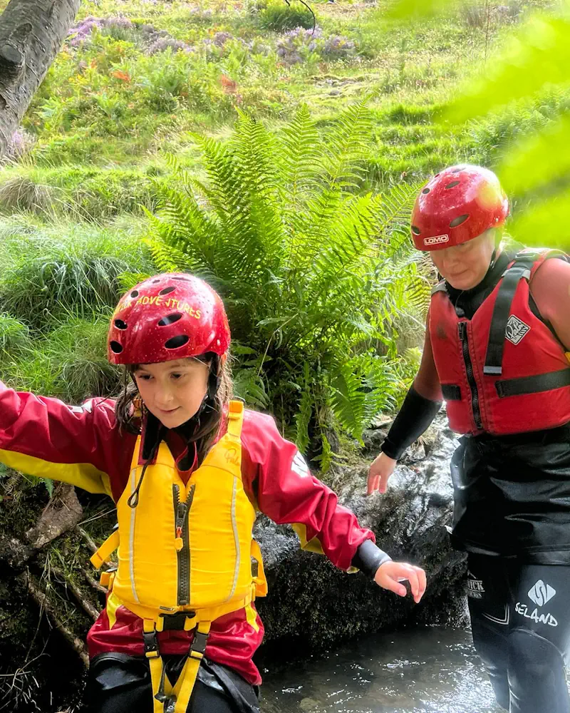 Mum and daughter wading through a river