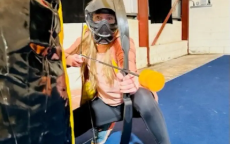 A woman poses looking at the camera with a bow and arrow in hand