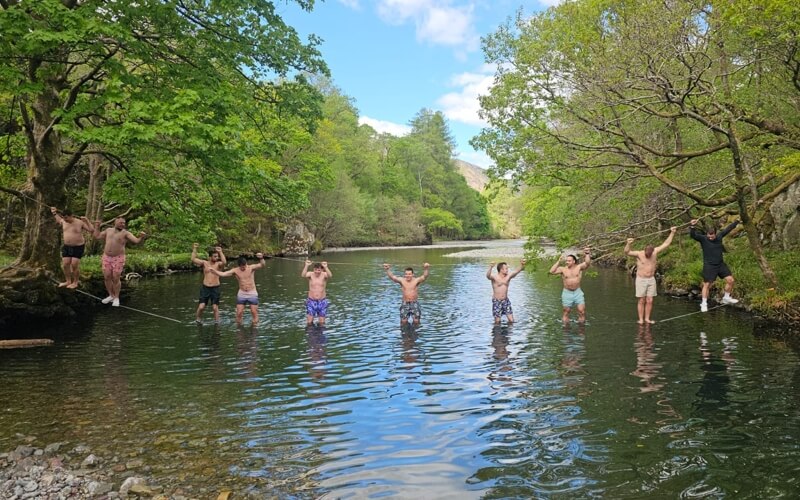 Group of people suspended on a rope bridge across a river