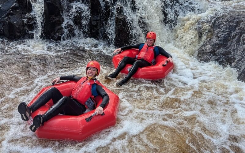 Two people on rubber tubes on rapids of the River Tees
